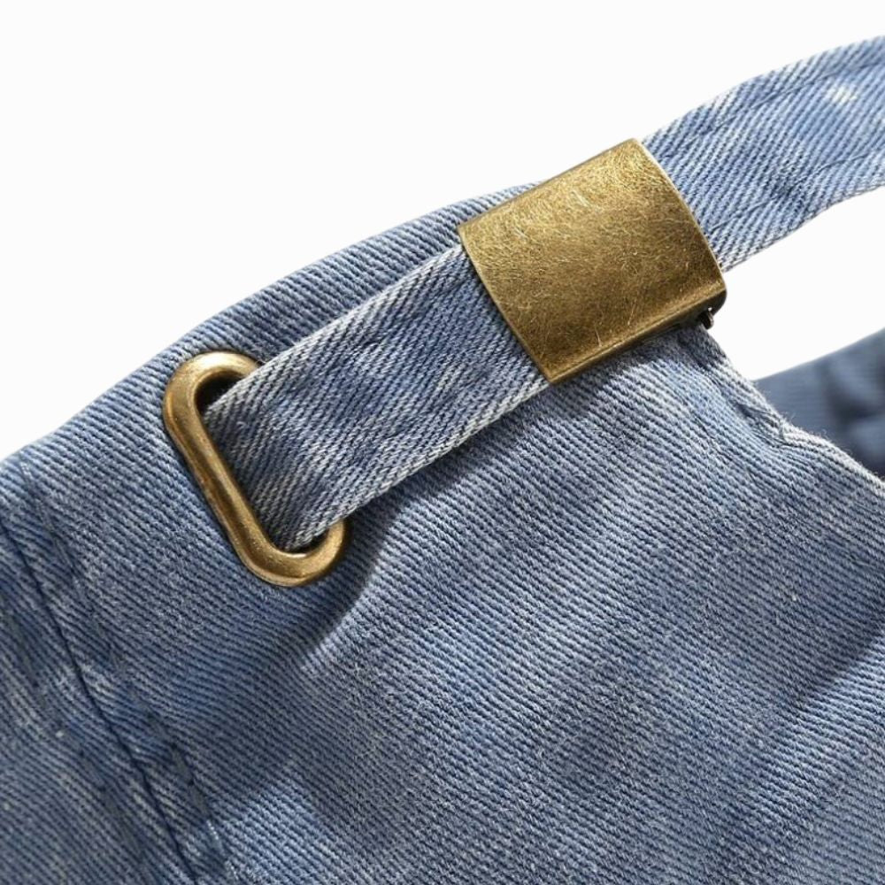 Close-up of blue denim fabric with a gold metal buckle on a white background