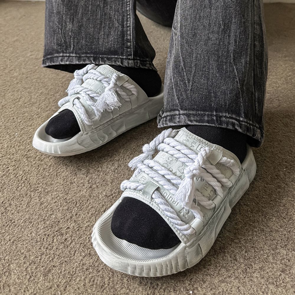 White sneakers with black soles worn by a person on a carpeted floor.
