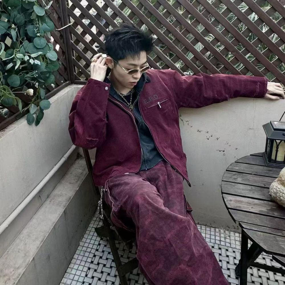 Person wearing a maroon jacket and pants sitting on a balcony.