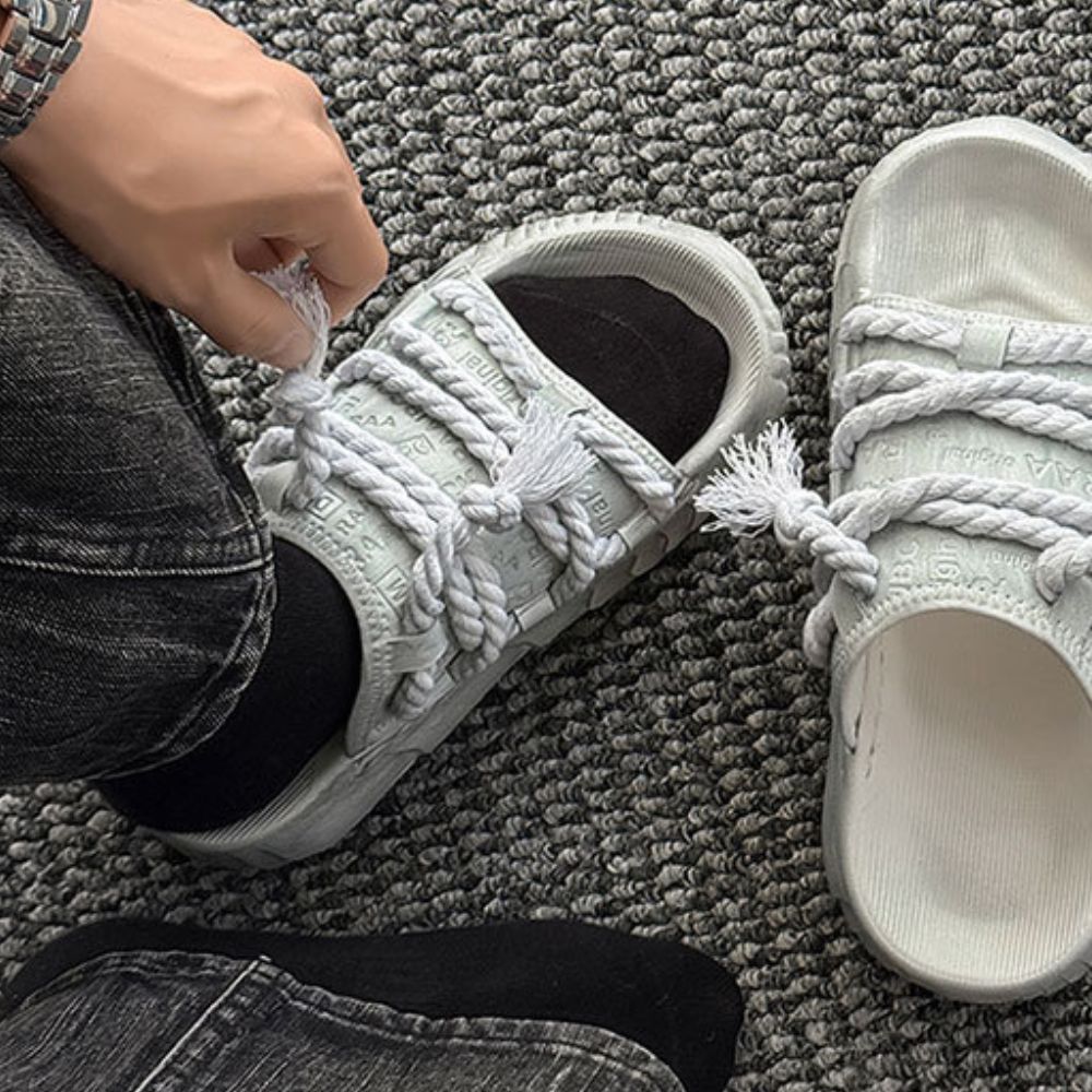 White sneakers with braided laces on a gray carpet