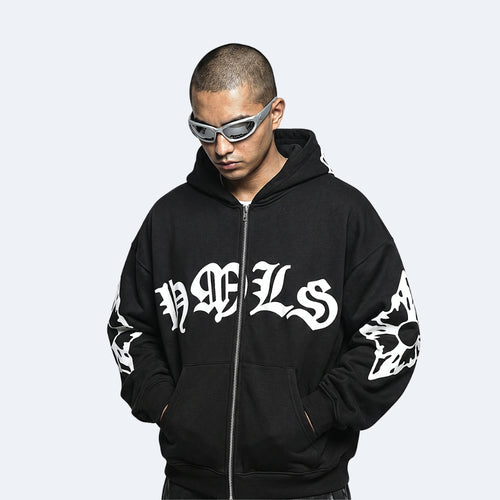 Black. A man wearing a black zip-up hoodie with white Gothic lettering on the chest and sleeve graphics, styled with gray-framed sunglasses.