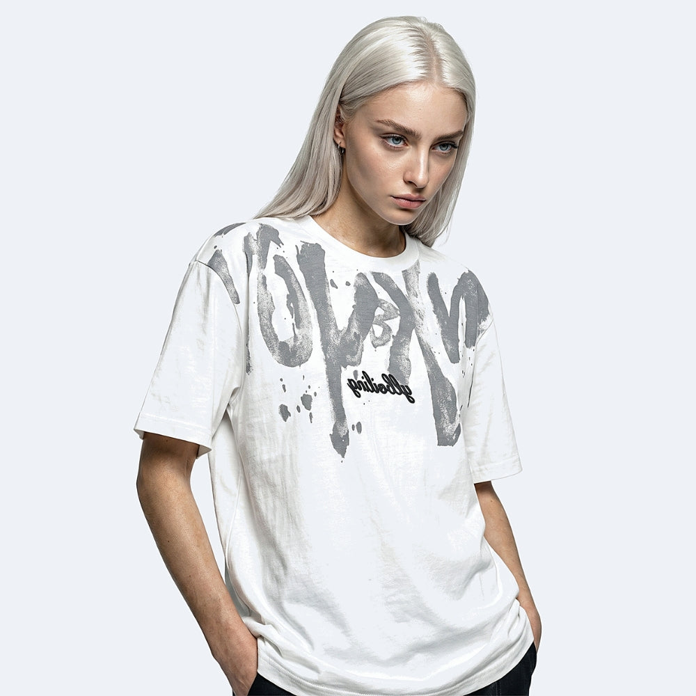 White. A model with platinum blonde hair wearing a white graphic t-shirt with a large gray and black spray-paint style logo on the front.