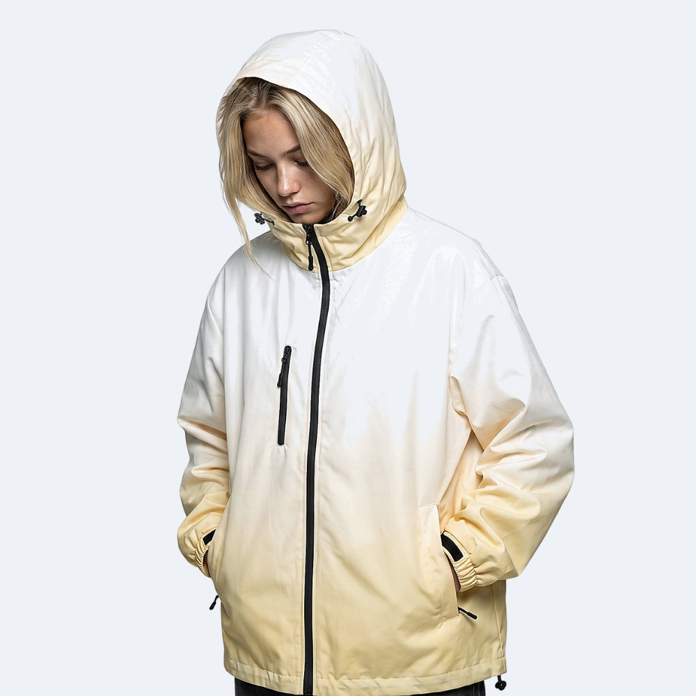 Creme. A model wearing a hooded jacket with a cream gradient color-blocked design and black zippers.