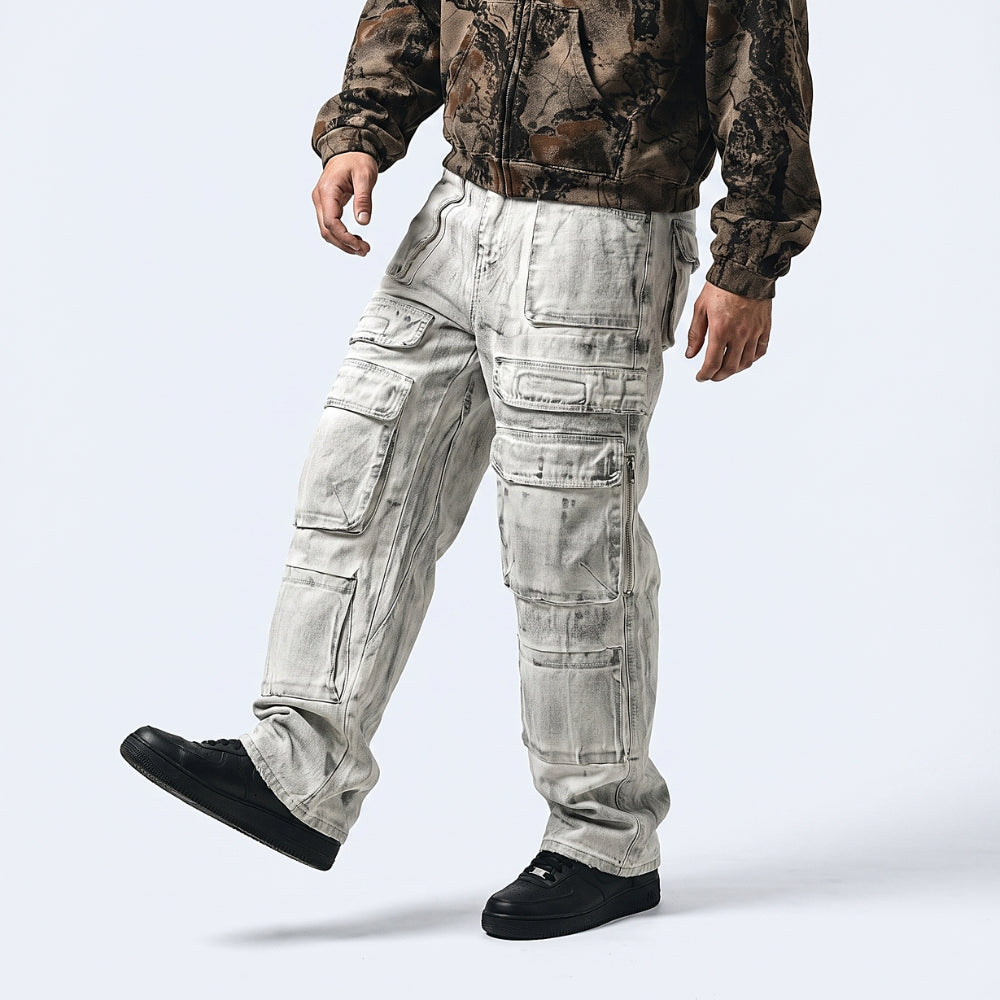 A person wearing washed light gray cargo pants with a brown camouflage jacket and black shoes, shown from the waist down against a light gray studio background.