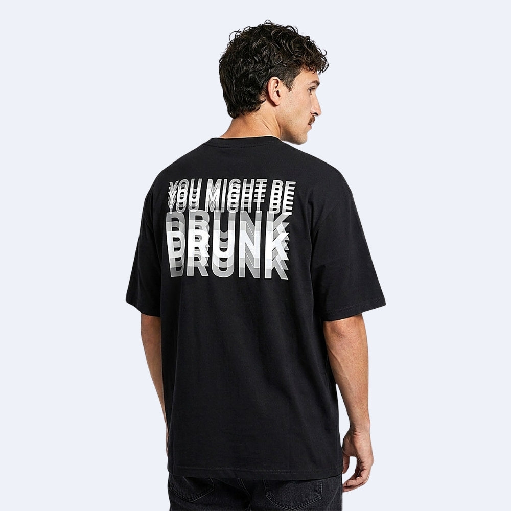 Black. KRUX You Might Be Drunk oversized tee in black, worn by a male model — back view showing the layered white DRUNK print