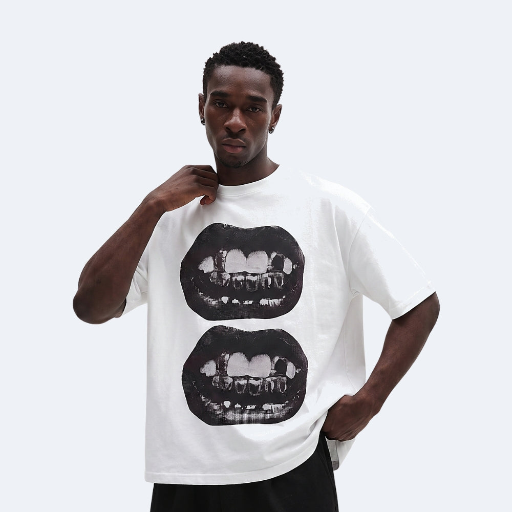 White. A man wearing a white oversized t-shirt with a graphic print of two black lips showing teeth.