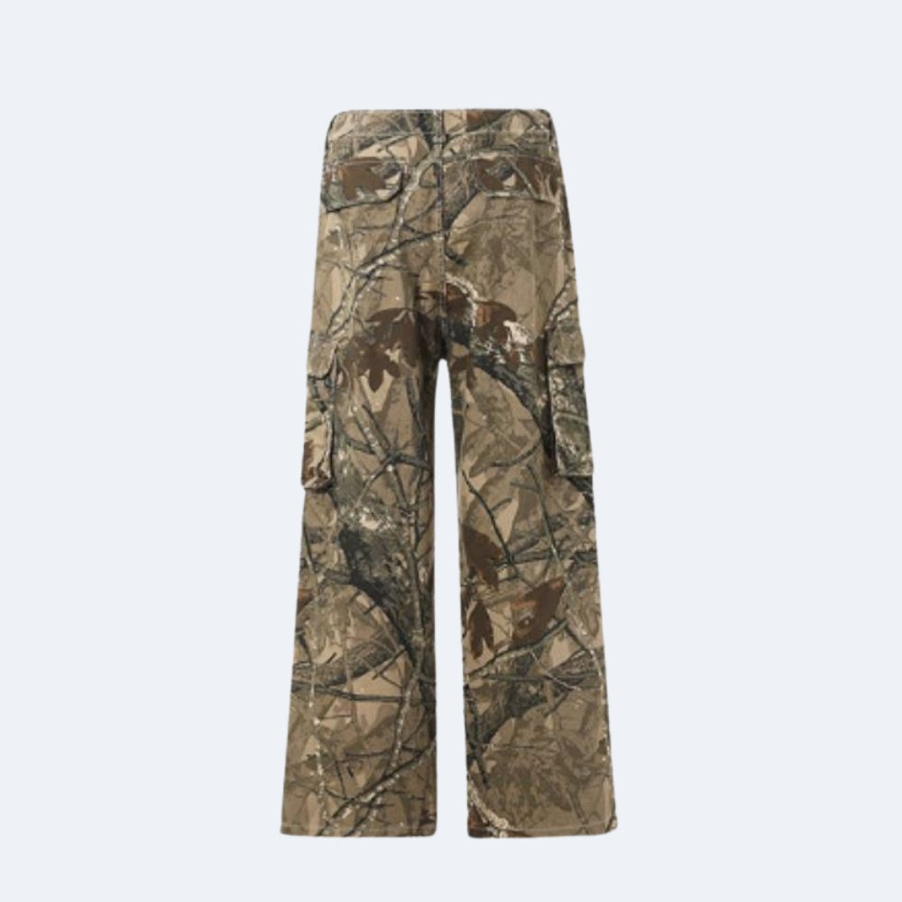 A pair of wide-leg cargo pants featuring a realistic brown and beige tree branch camouflage pattern, shown against a plain light gray background.