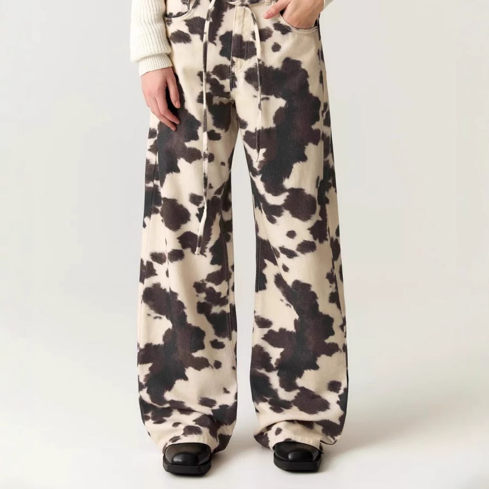 Cow print pants worn by a person on a white background