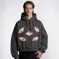 Person wearing a gray hoodie with eye designs on a white background