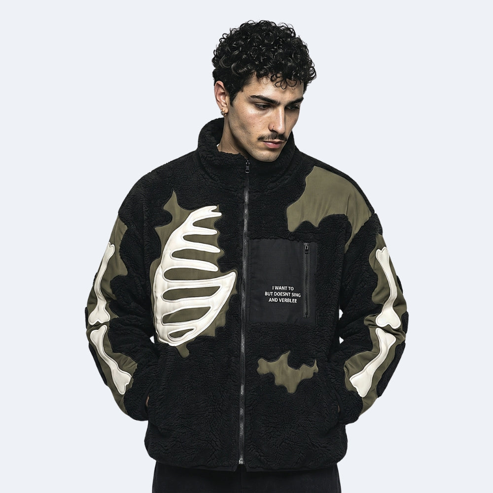 Black. A man wearing a black fleece zip-up jacket with green camouflage pattern and bone graphic details.