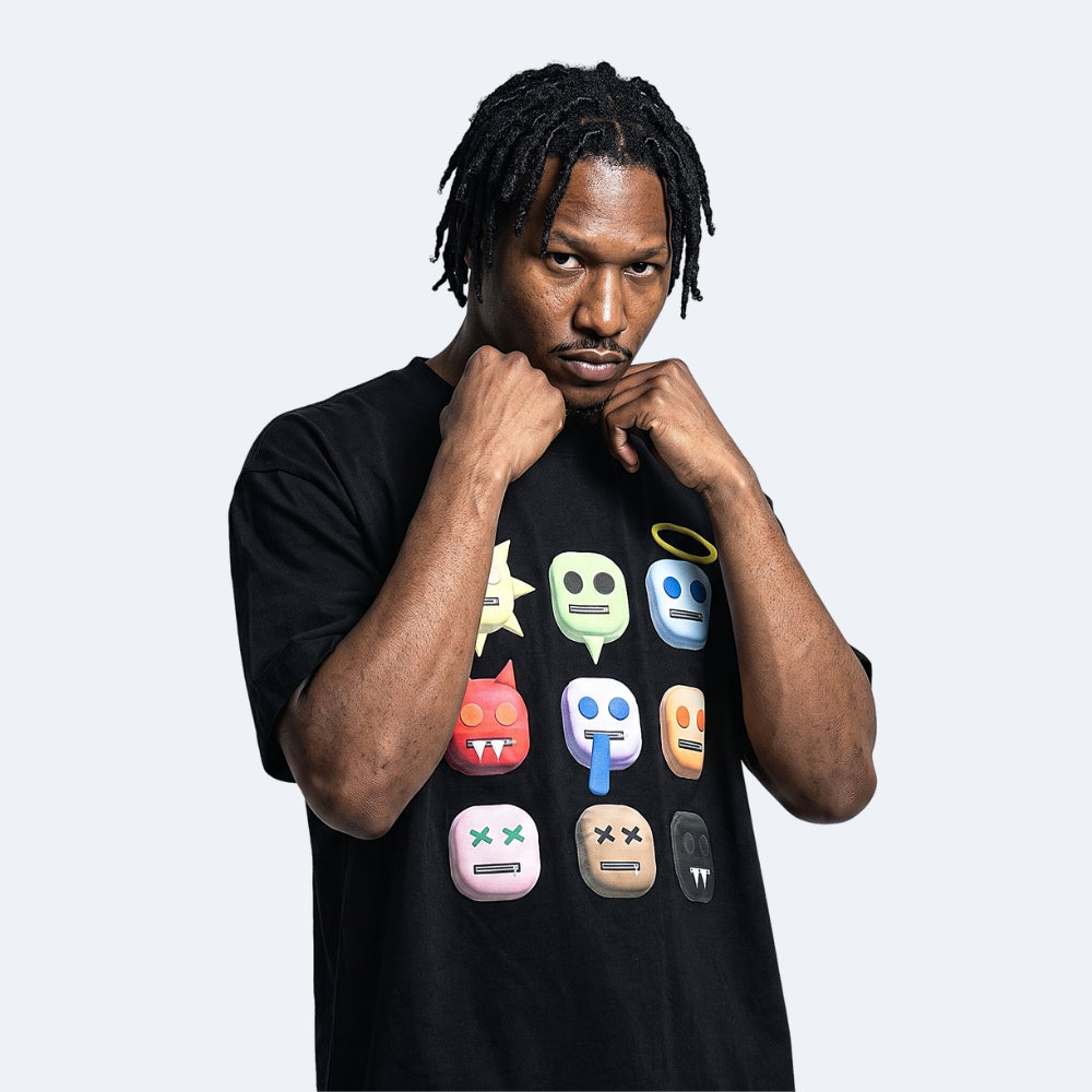 Black. A man wearing a black crewneck t-shirt with a colorful graphic print of various emoji-style faces.