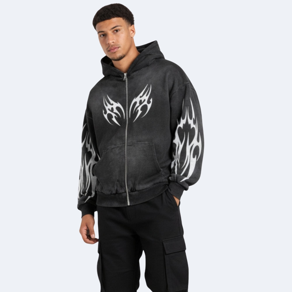 Black. A man wearing a black washed zip-up hoodie with white tribal flame graphics on the chest and sleeves, paired with black cargo pants.