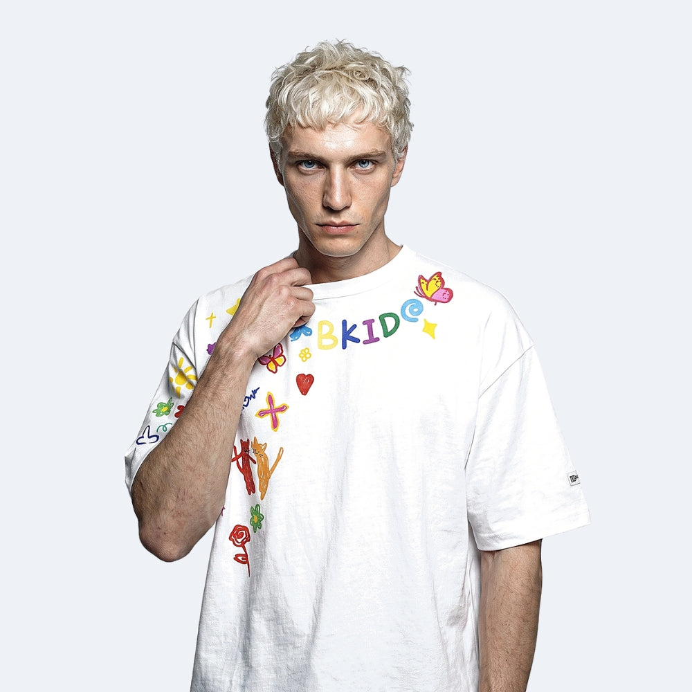 White. A blonde male model wearing a white short-sleeve t-shirt with colorful text and doodle graphics on the front.