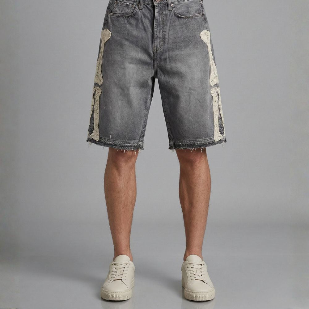 Denim shorts with patchwork design worn by a person on a gray background
