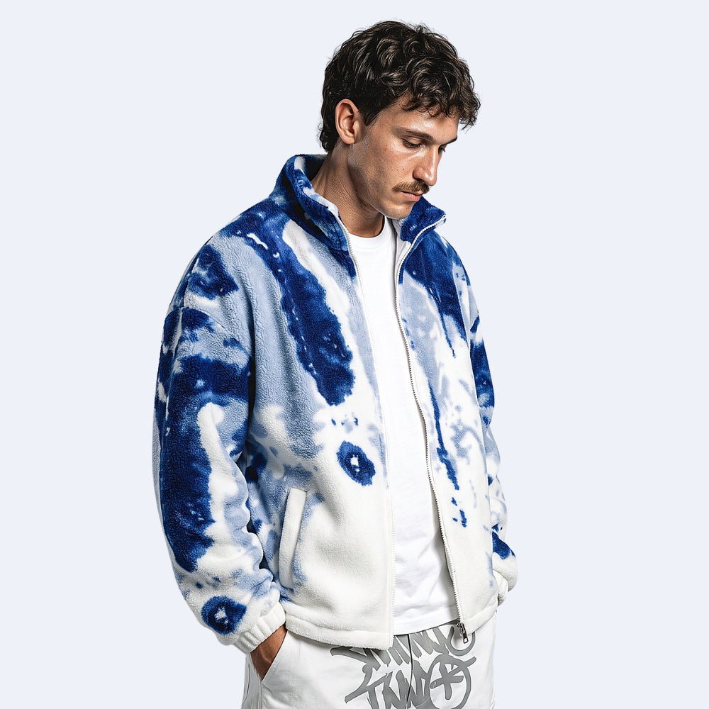 Blue. A man wearing a blue and white tie-dye fleece zip-up jacket over a white t-shirt and white pants.