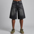 Black denim shorts worn by a person on a gray background