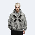A model with platinum blonde hair wearing a gray and black marbled hoodie with a large black geometric cross graphic on the chest, set against a plain light gray background.