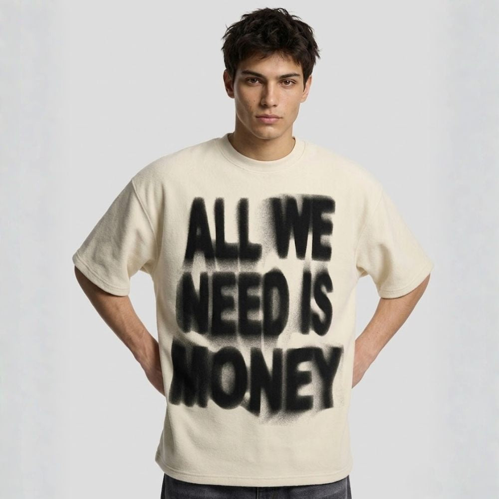 Man wearing a beige t-shirt with 'All We Need Is Money' text on a plain background