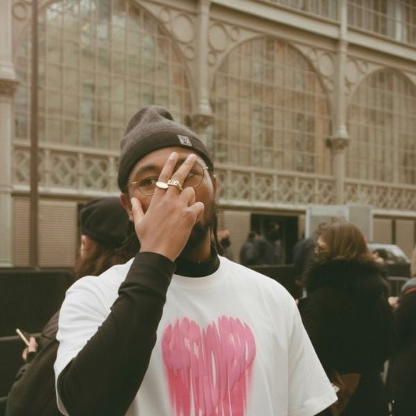 Person wearing a white t-shirt with pink design and a beanie in an indoor setting