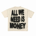 Beige t-shirt with black spray-paint text 'ALL WE NEED IS MONEY' on a white background