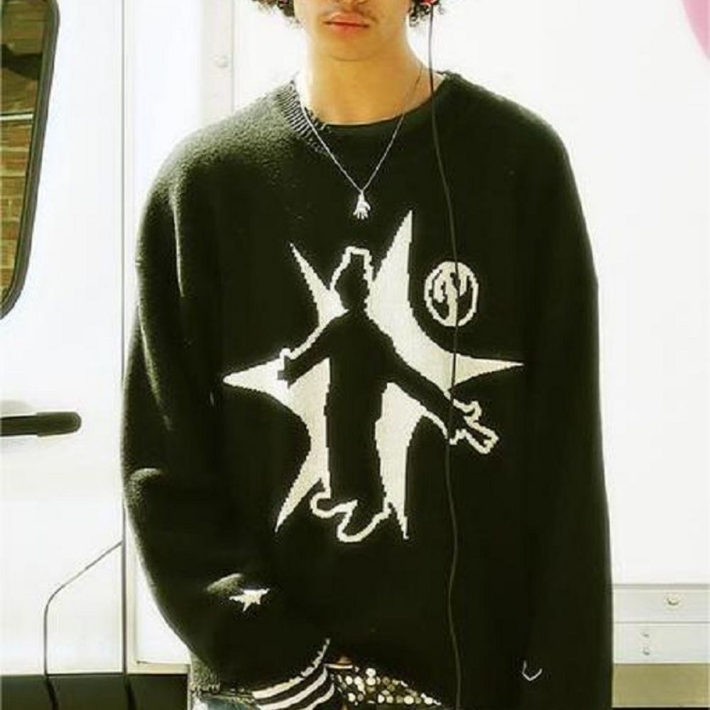 Person wearing a black sweater with a white graphic design indoors.