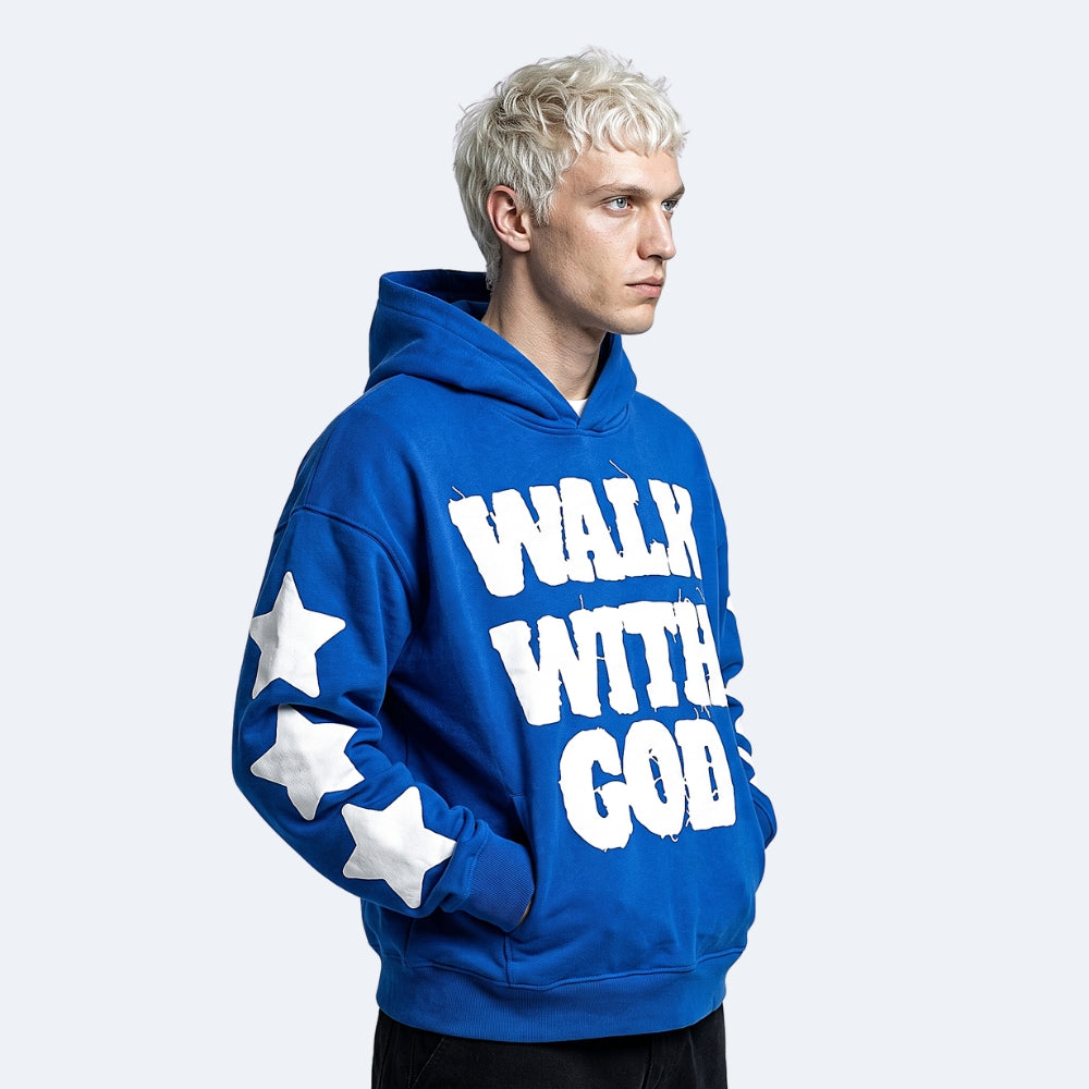 Royal Blue. A man with platinum blonde hair wearing a royal blue hoodie with WALK WITH GOD printed in white distressed letters on the front and three white stars on the sleeve.