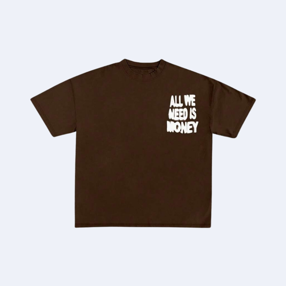 A dark brown short-sleeve t-shirt with the phrase 'ALL WE NEED IS MONEY' printed in white distressed font on the left chest, displayed flat against a light gray background.