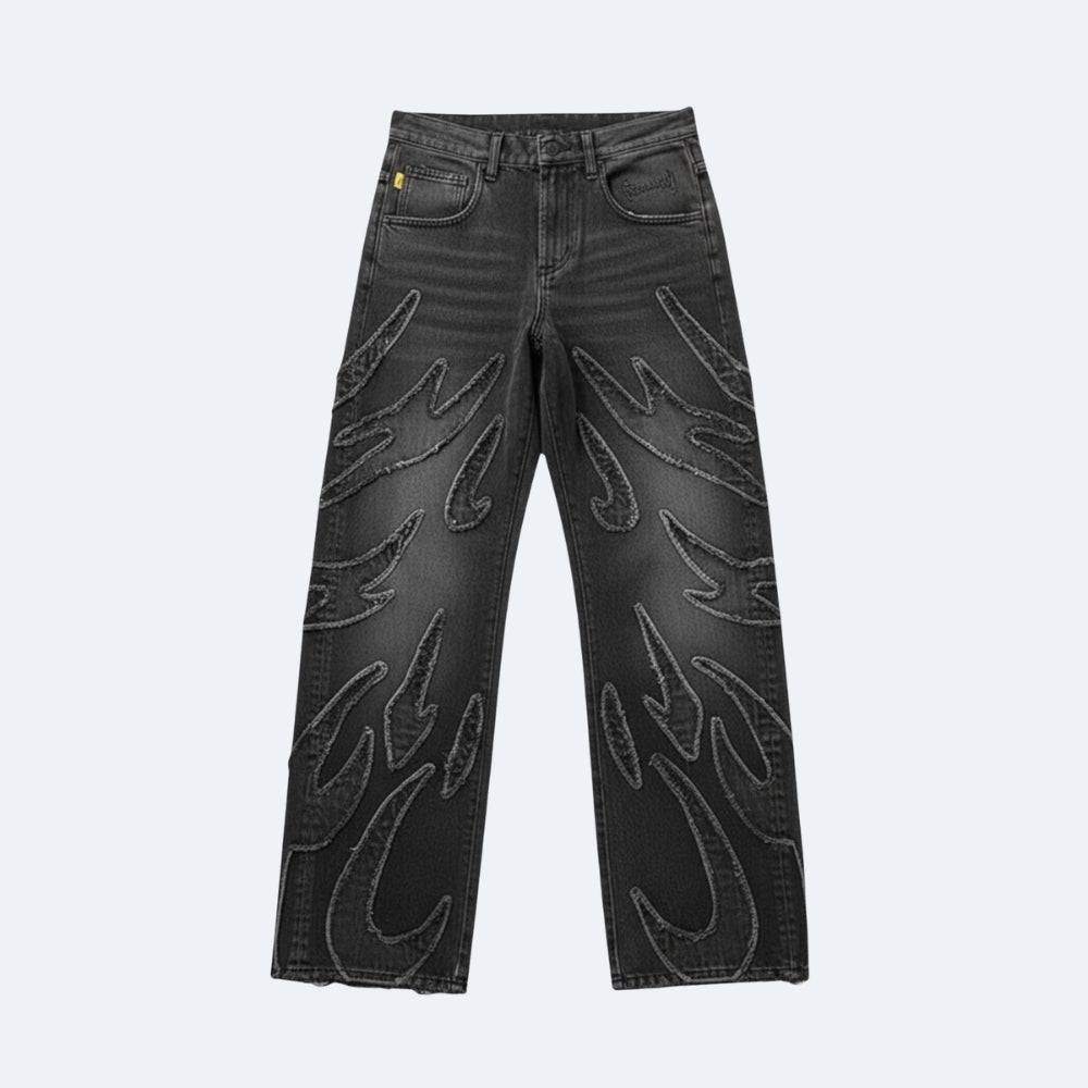 Black denim jeans with large, raised flame-like embroidered patterns on the front of both legs, shown against a light gray background.