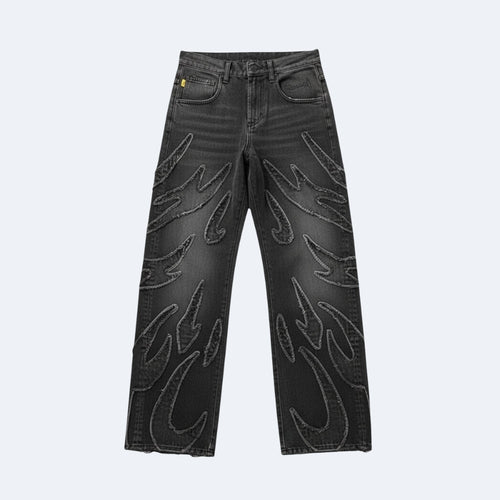 Black denim jeans with large, raised flame-like embroidered patterns on the front of both legs, shown against a light gray background.