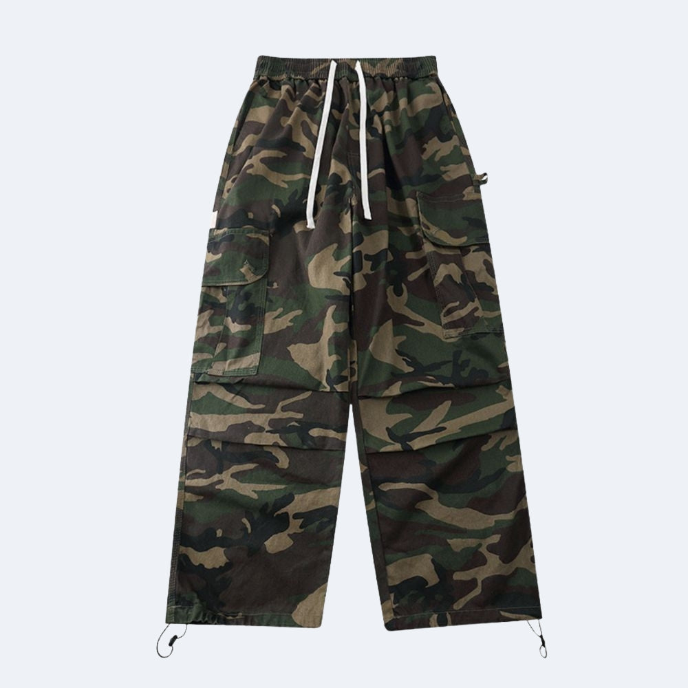 A pair of camouflage cargo pants with a green, brown, and black camo pattern, featuring a white drawstring at the elastic waist and adjustable drawstrings at the ankle cuffs, shown against a light gray background.