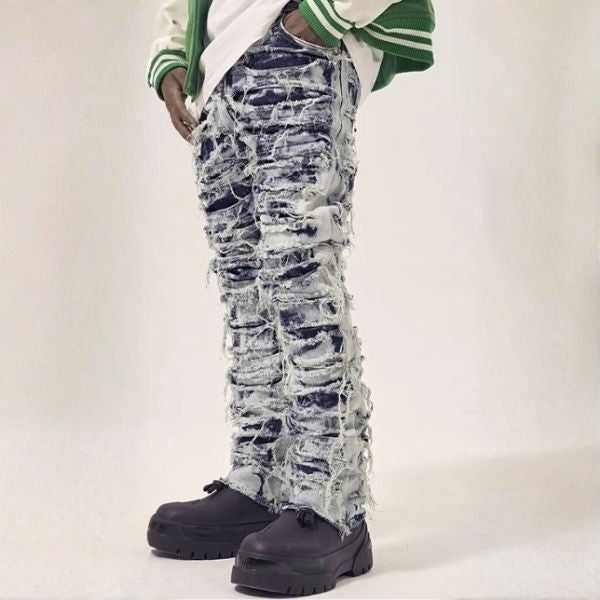 Person wearing distressed blue jeans and black shoes on a white background