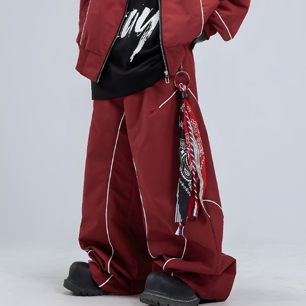 Person wearing a red outfit with a black bag and colorful scarf on a light gray background