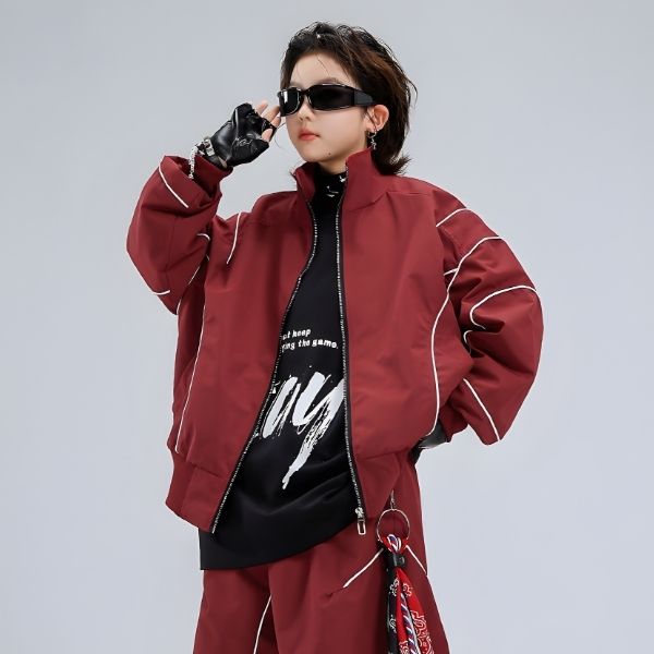 Person wearing a red jacket and black outfit with sunglasses on a gray background