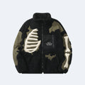 Black. A black and olive green fleece jacket with bone graphic appliqués on the chest and sleeve, and a black chest pocket with white text.