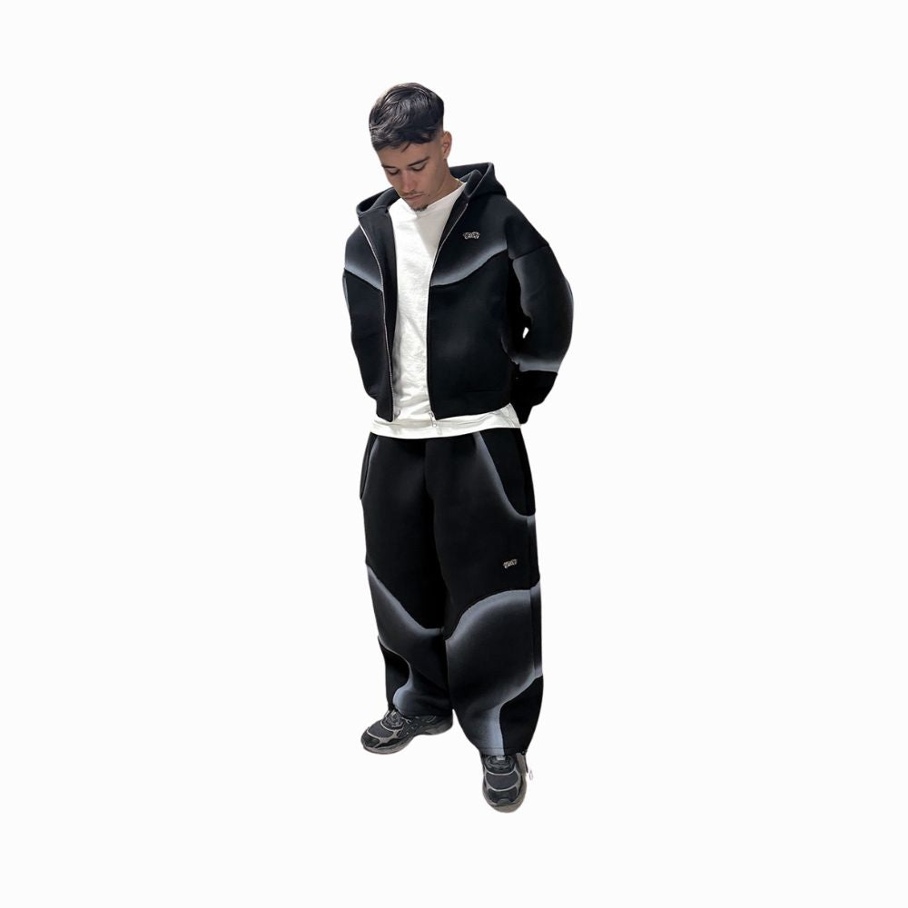 Person wearing a black and gray jacket and pants on a white background