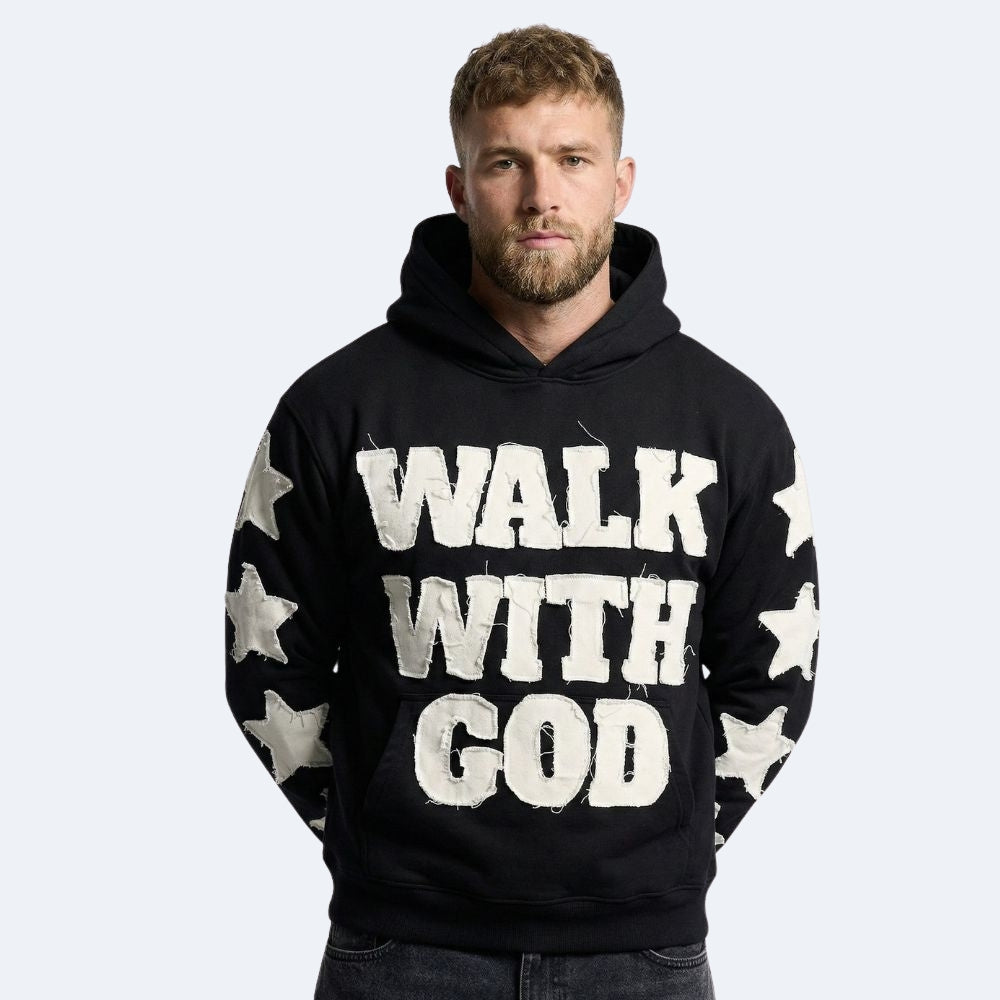 Black. A man wearing a black pullover hoodie with WALK WITH GOD printed in distressed white letters across the chest, and white stars down both sleeves.