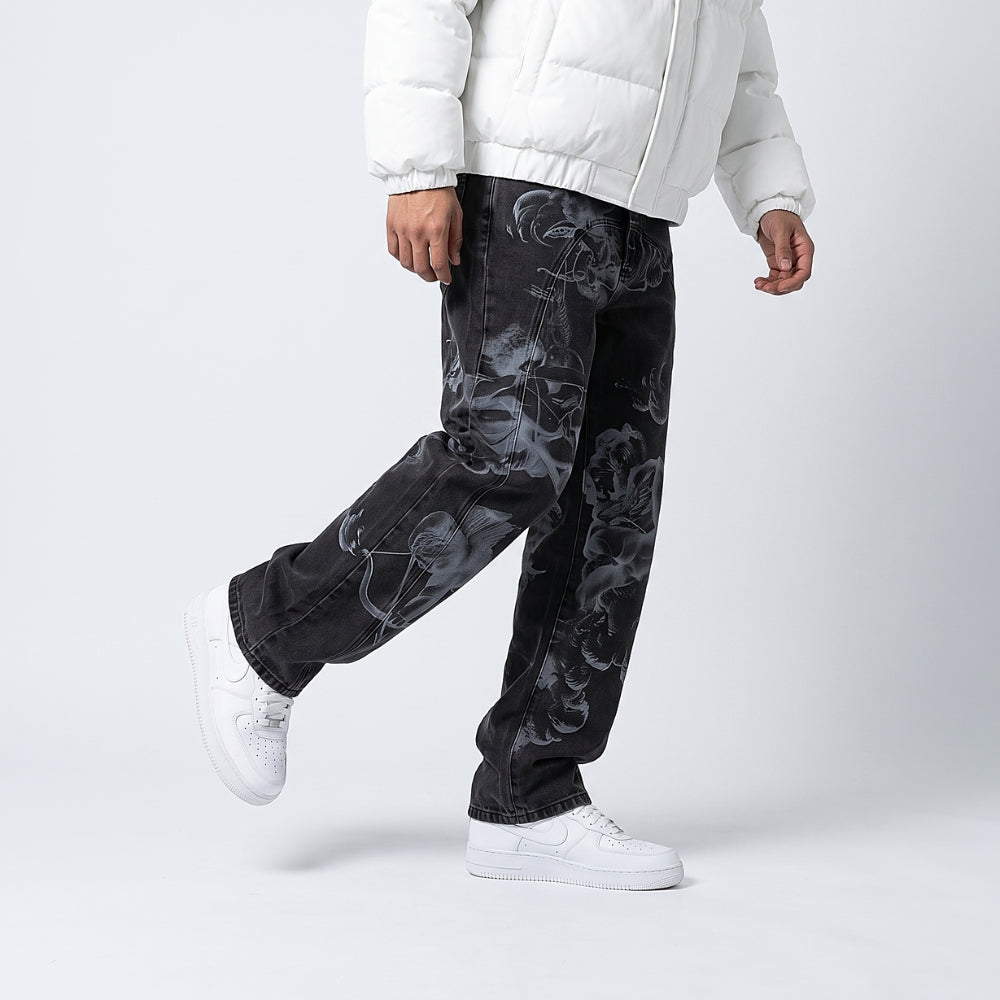 Black. A person wearing black denim jeans with a gray smoky graphic print, styled with a white puffer jacket and white sneakers, captured from the waist down.