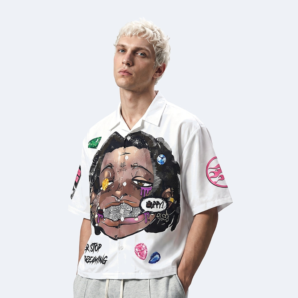 A model with platinum blonde hair wearing a white short-sleeve button-up shirt with a large graffiti-style graphic of a face on the front, styled with light gray sweatpants against a light gray studio background.