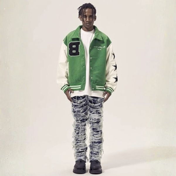 Person wearing a green and white varsity jacket with a number 8 patch on a plain background