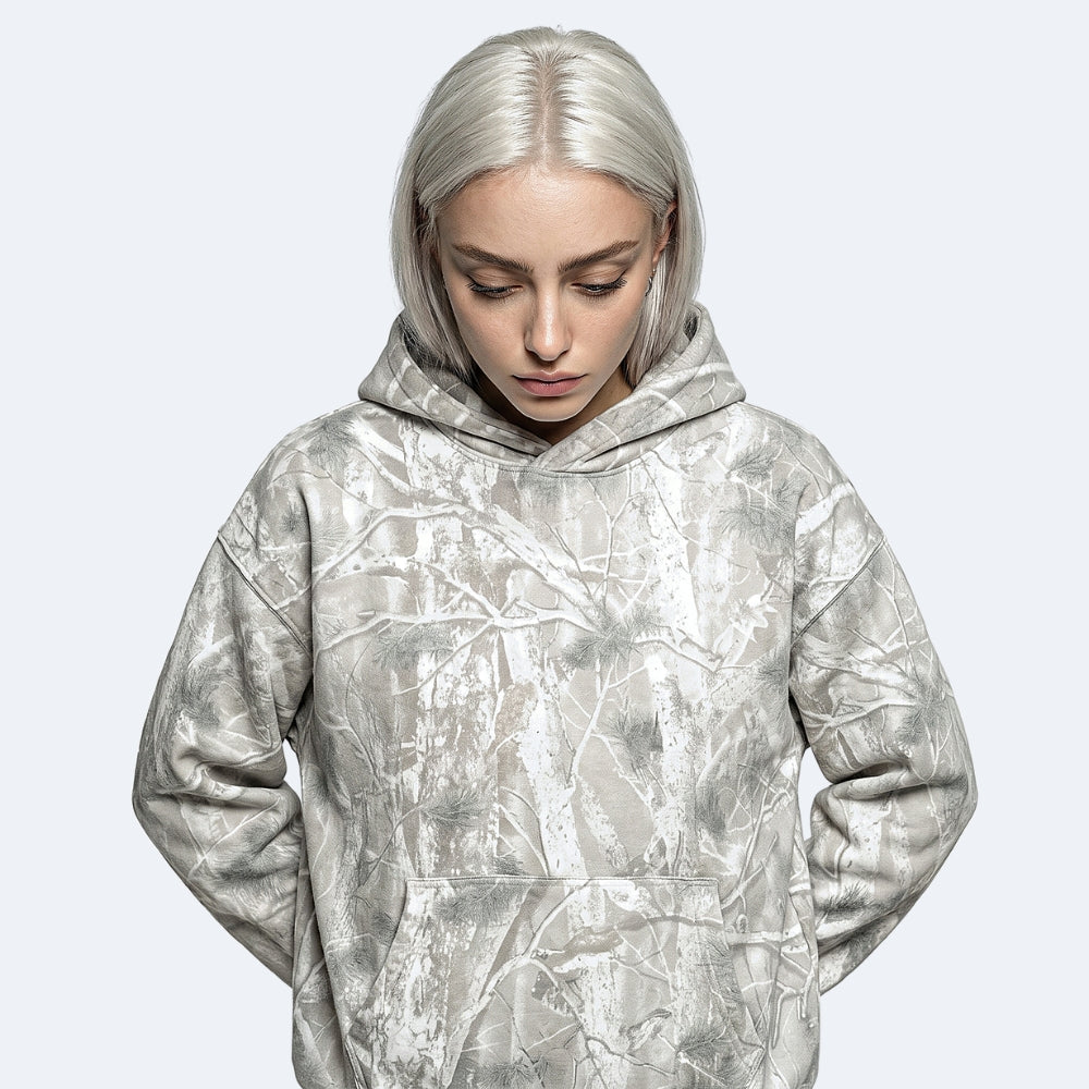 Veins. A model with platinum blonde hair wearing an oversized pullover hoodie with a silver and gray abstract tree branch pattern.