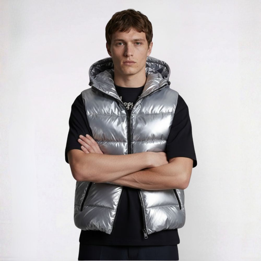 Man wearing a reflective silver puffer vest over a black shirt on a white background