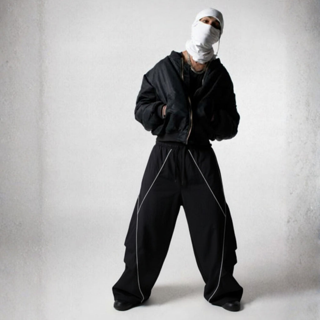 Person wearing a black tracksuit and white balaclava against a plain background