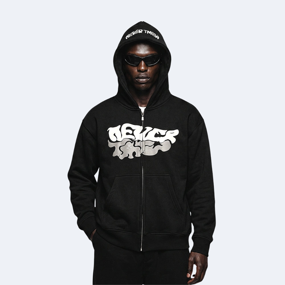 Black. A man wearing a black zip-up hoodie with a large white and gray graffiti-style graphic on the front, black pants, and black sunglasses.