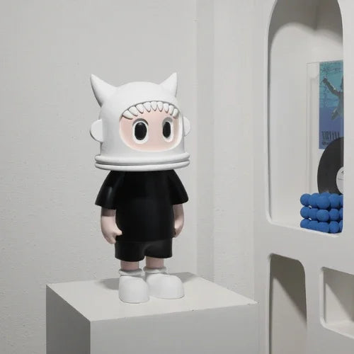 Toy figure with a white helmet and black outfit on a white pedestal against a gray wall.