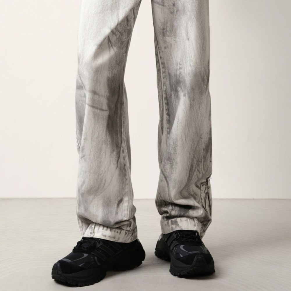 Person wearing light gray pants and black shoes on a plain background