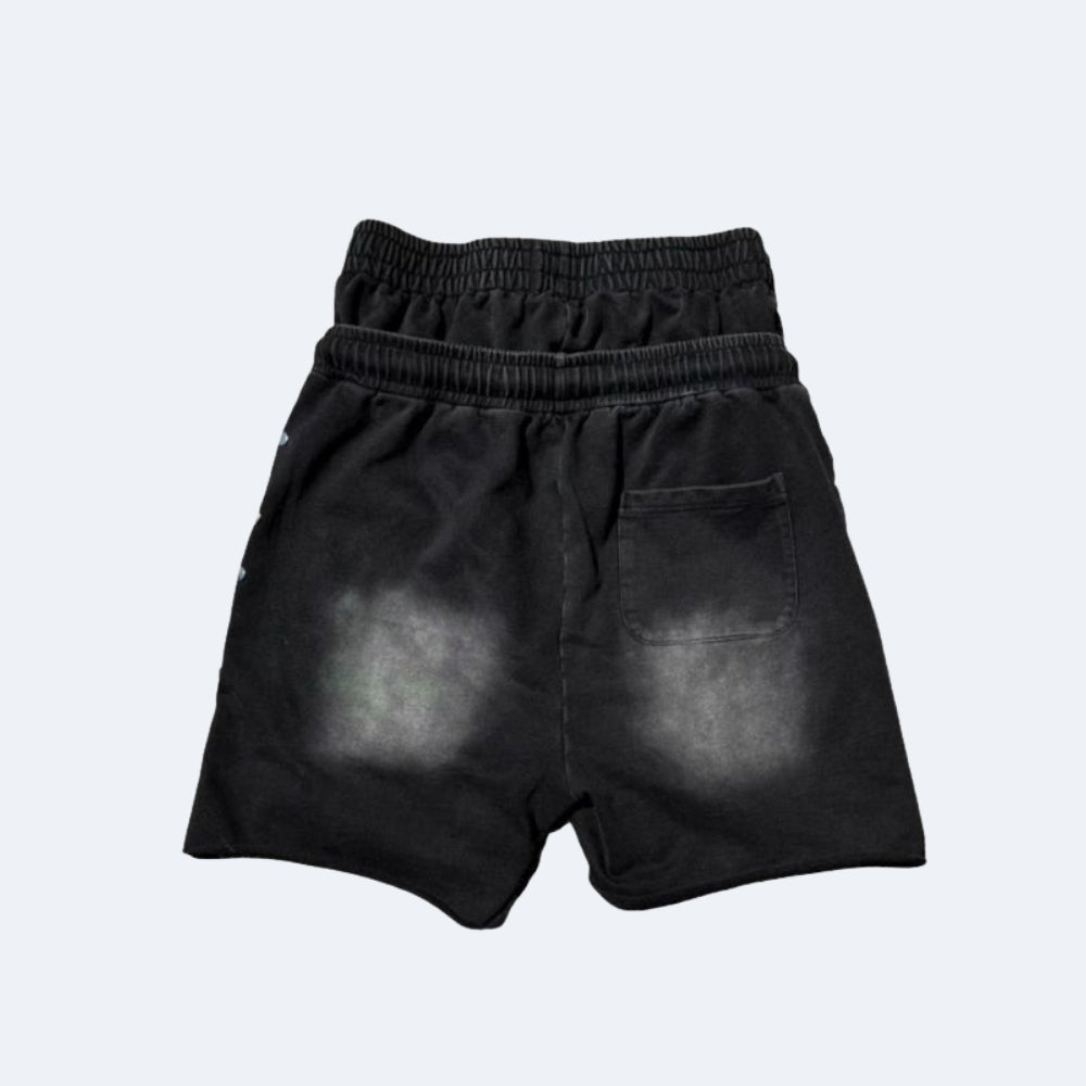 Black athletic shorts with a distressed, faded gray wash on the back pockets and sides, featuring an elastic waistband and a single back patch pocket, shown against a light gray background.