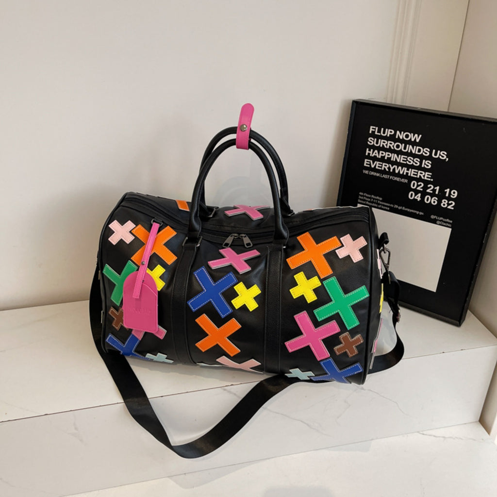 Black duffel bag with colorful geometric patterns on a white surface.