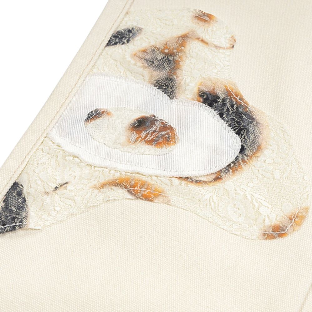 Close-up of a white shoe with black and brown accents on a beige fabric background