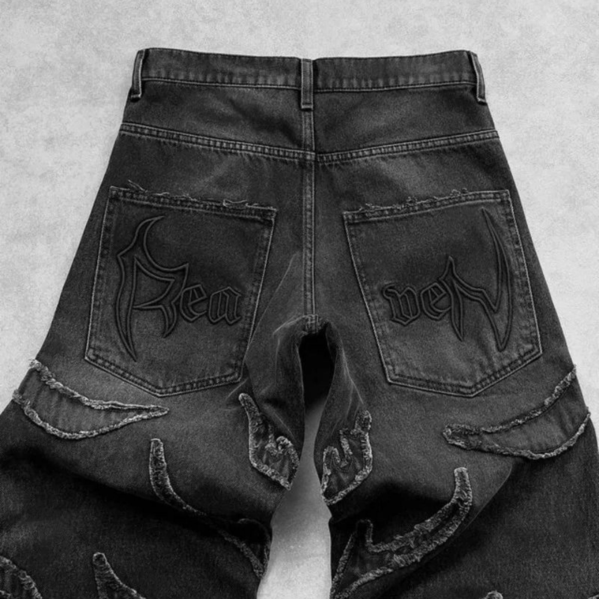 Black denim jeans with 'New' branding on the back pockets against a gray background