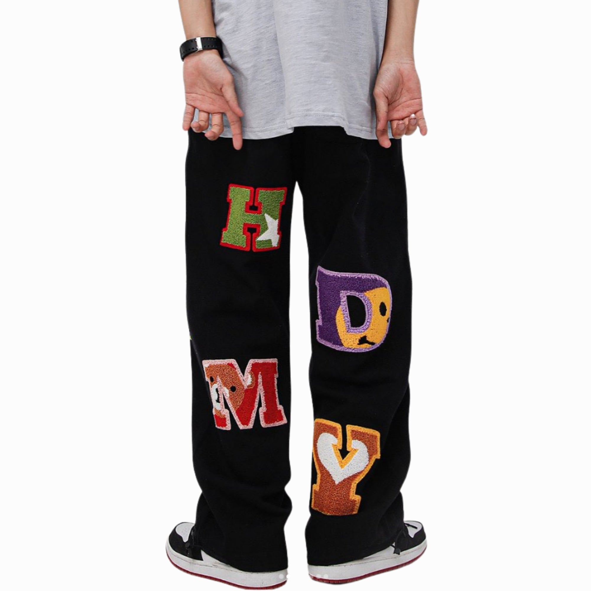 Black pants with colorful letters worn by a person on a white background